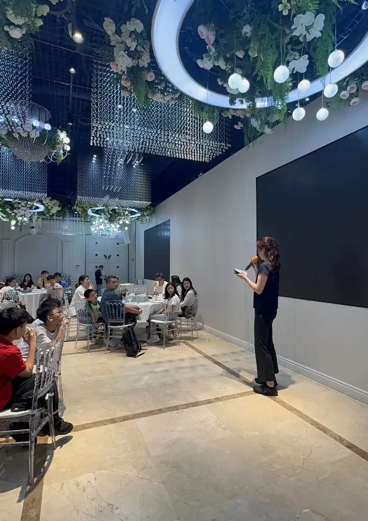 An instructor with a microphone addresses the seated children at the opening ceremony