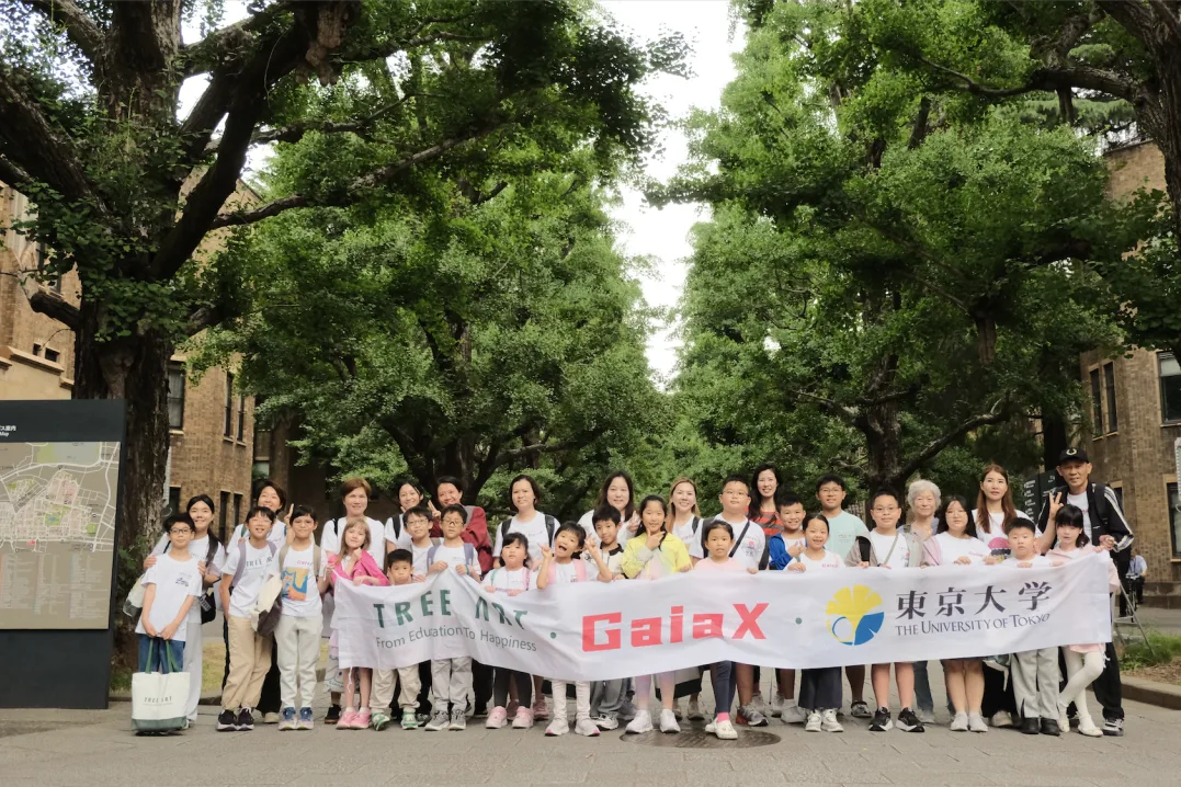 Group photo under the ginkgo trees at the University of Tokyo behind a TREE ART and GaiaX banner