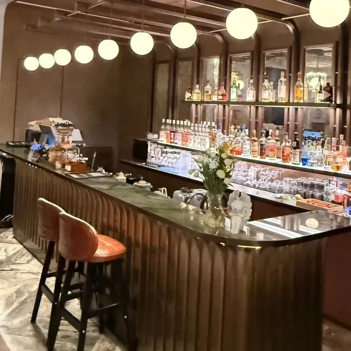 A hotel bar with globe pendant lights, a stone counter and shelves of bottles