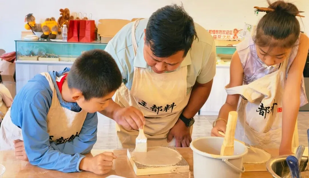 Instructor and two children brushing white primer onto a clay board