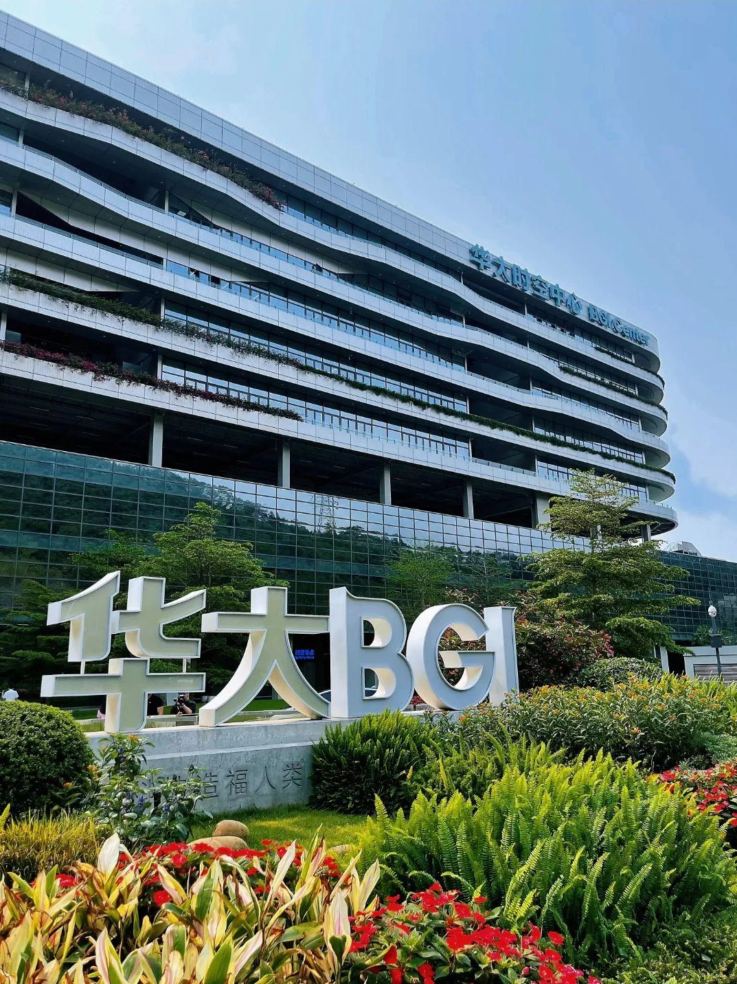 The curved BGI Center building in Shenzhen behind a large steel BGI monument sign.