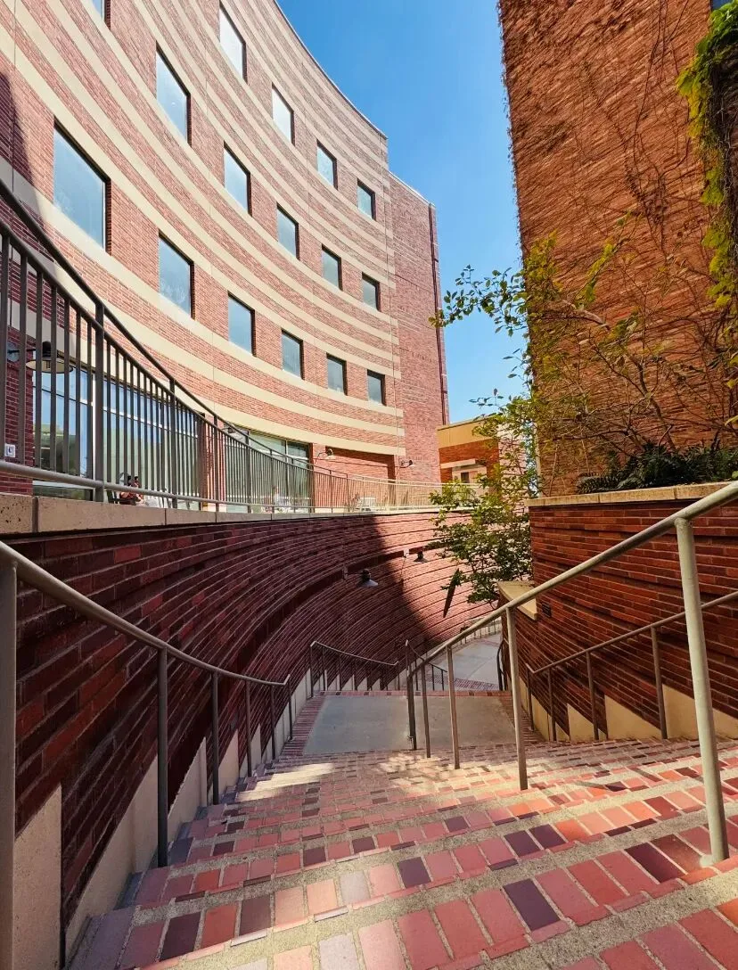 A curved brick building above a sunken brick stairway on the UCLA campus.