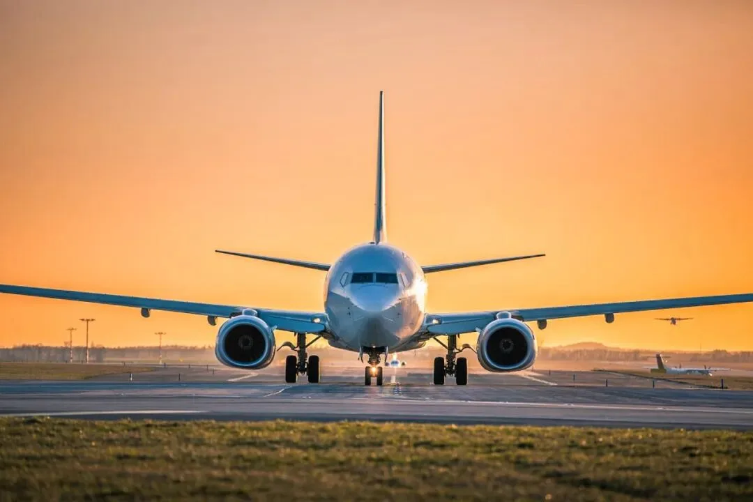An airliner facing the camera on a runway beneath an orange sunset sky.