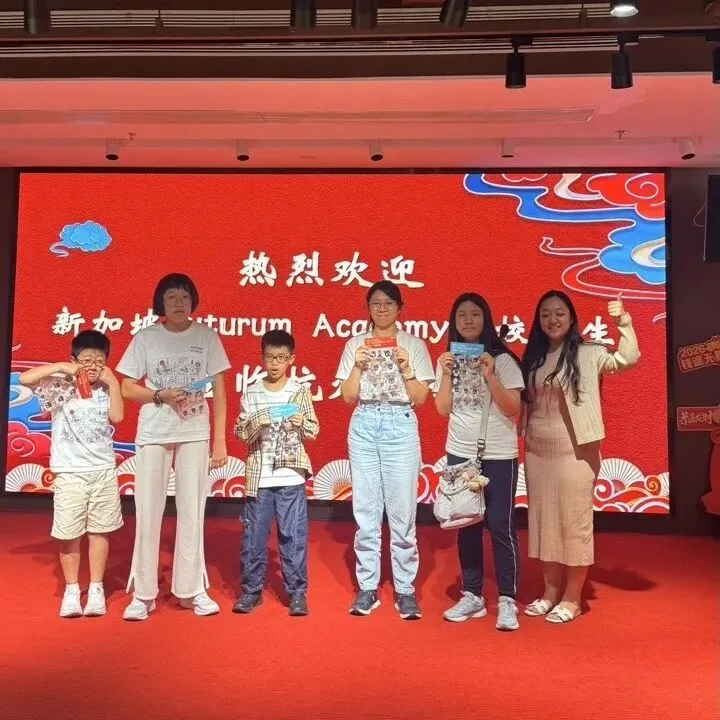 Children hold their prizes on stage before a red screen welcoming Futurum Academy