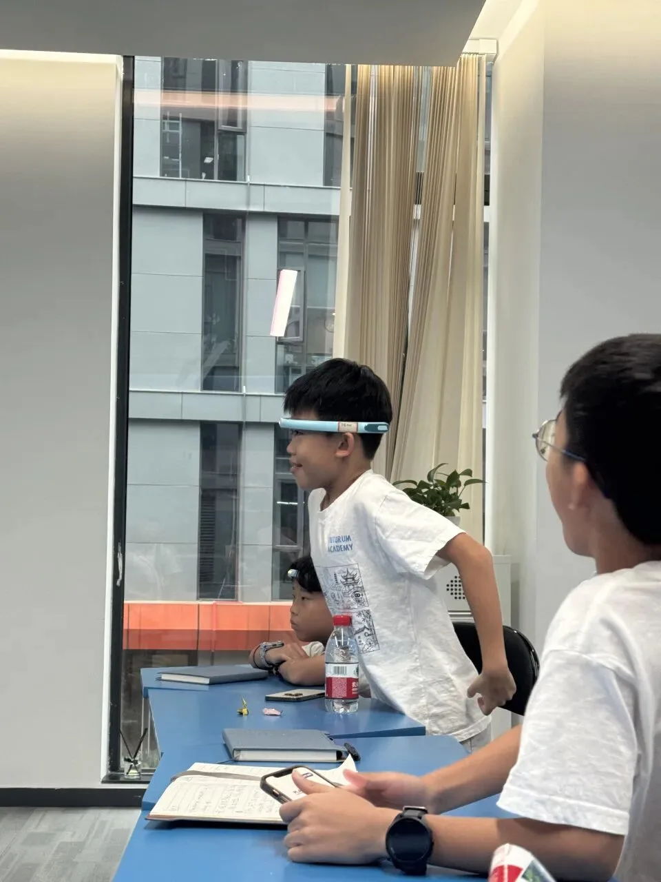 A boy wearing a brainwave focus headband stands at his desk during the demonstration