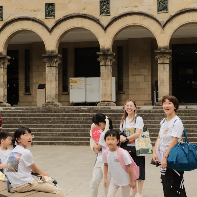 Students and teachers on the steps of an arched stone building on campus