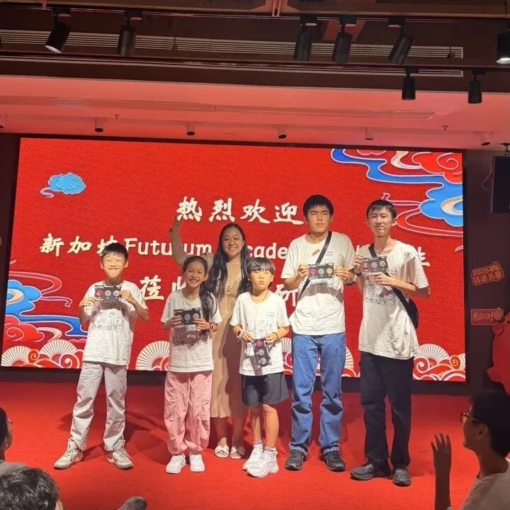 Five children and their instructor hold boxed prizes on the closing ceremony stage