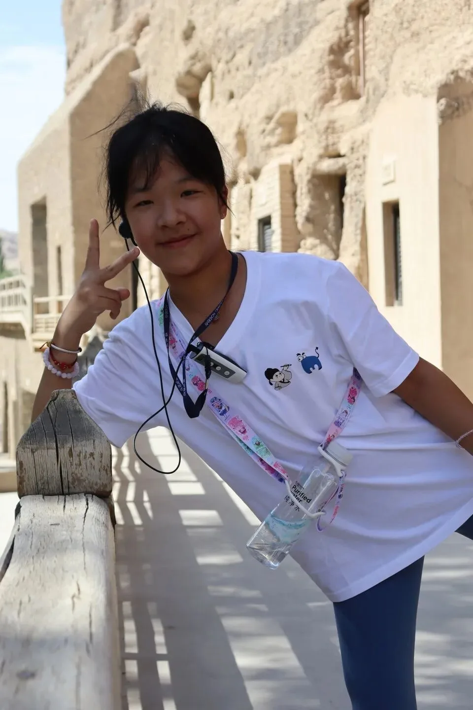 Girl with an audio-guide earpiece on the walkway below the cliff-face grottoes