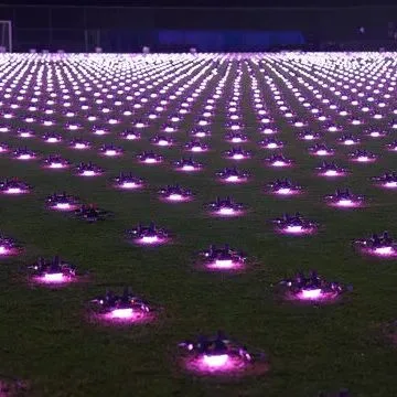 Hundreds of drones lined up on a night field, each glowing pink before a light show.