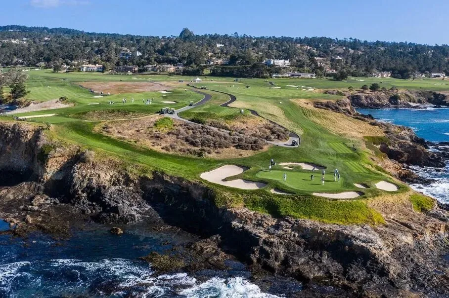 A clifftop golf green and bunkers on a rocky headland above the Pacific.