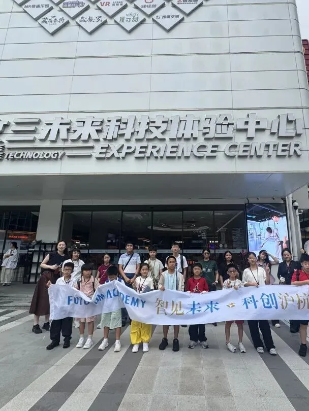 The group holds its banner outside the entrance of a future technology experience centre