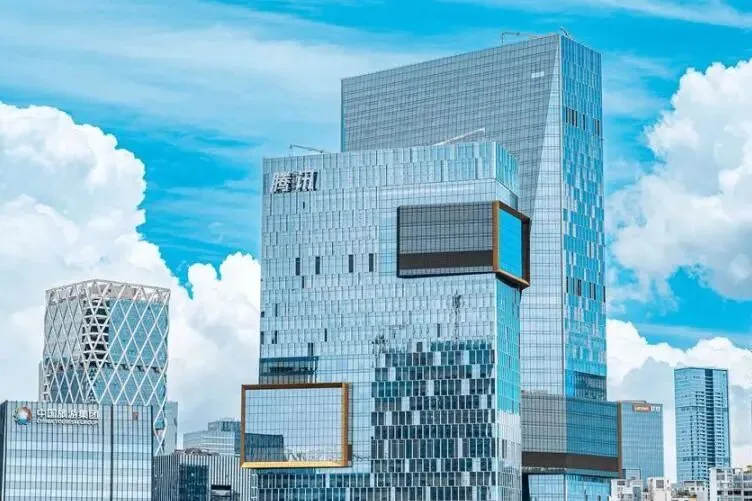 Tencent's Binhai headquarters in Shenzhen with cantilevered sky boxes under bright clouds.
