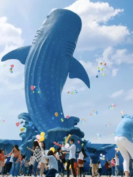 Visitors with balloons dancing around the giant blue whale shark statue at Chimelong Ocean Kingdom.