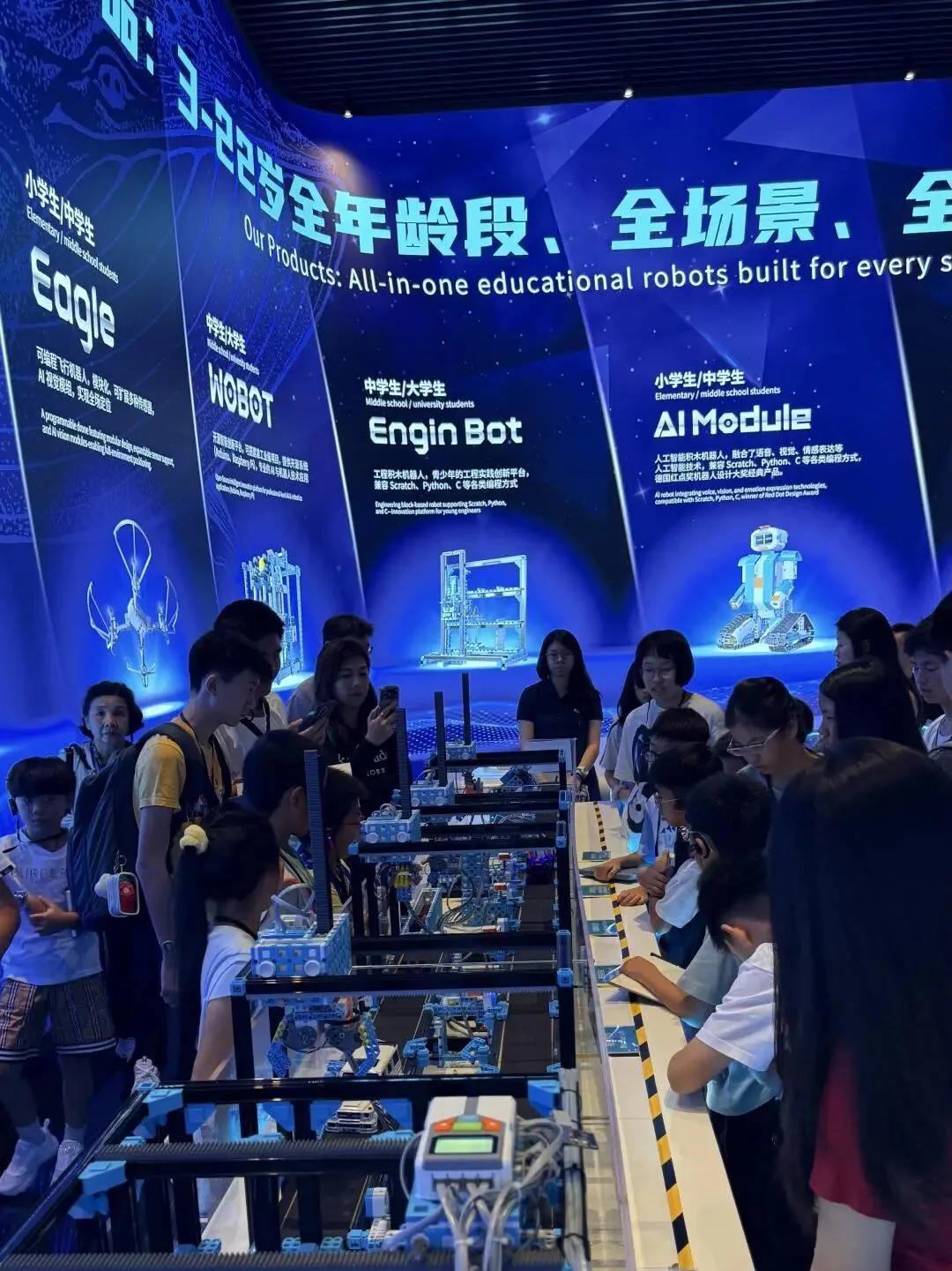 Children handle robot kits below EnjoyAI product panels for Eagle, WOBOT, Engin Bot and AI Module