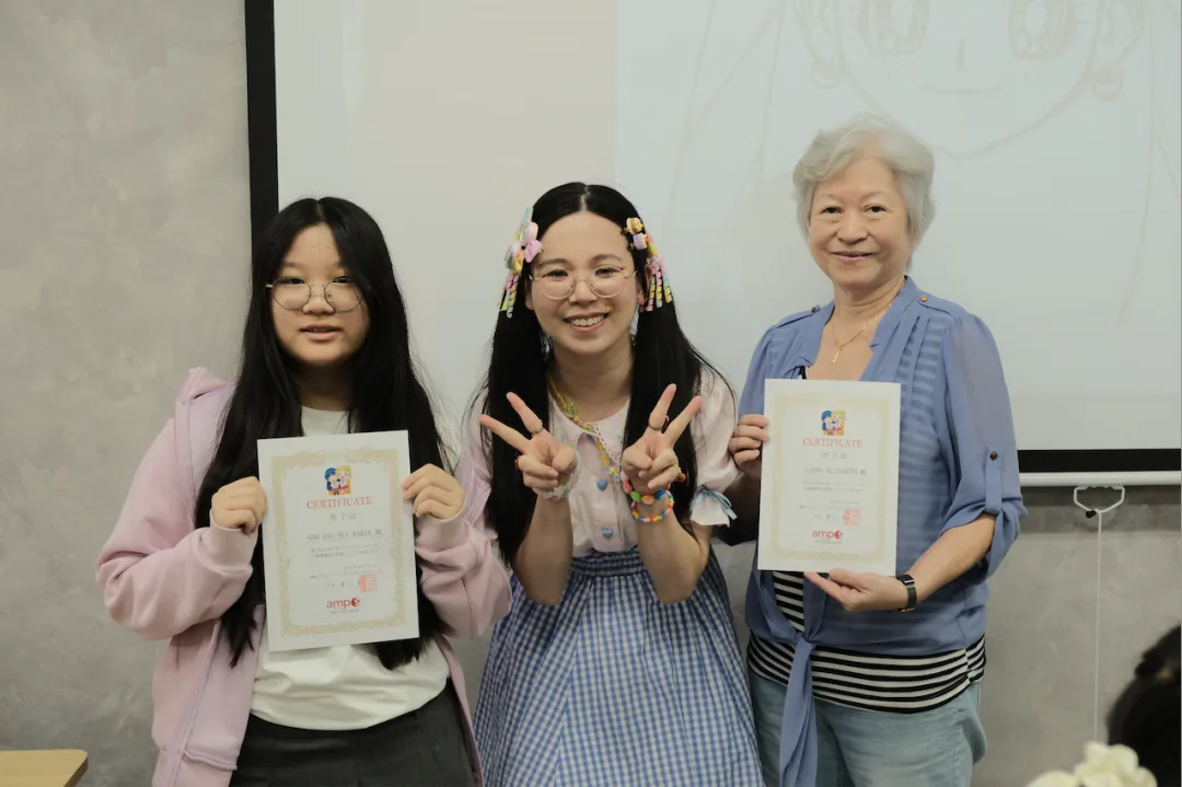 Two students and a grandmother holding their amps certificates in the classroom