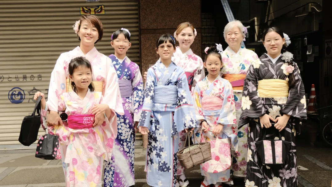 Mothers and daughters in summer kimono posing together on a shopping street