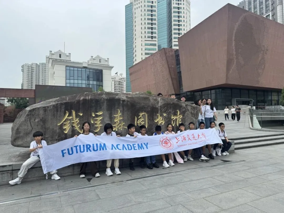 Campers hold a Futurum Academy banner in front of the Qian Xuesen Library's engraved stone