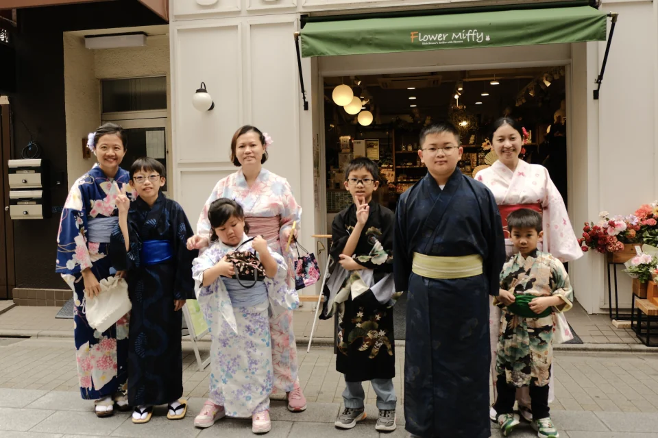 Families in kimono posing outside a flower shop in Asakusa