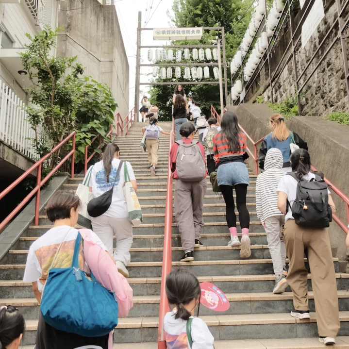 The group climbing the long stone stairway to Suga Shrine under a row of lanterns