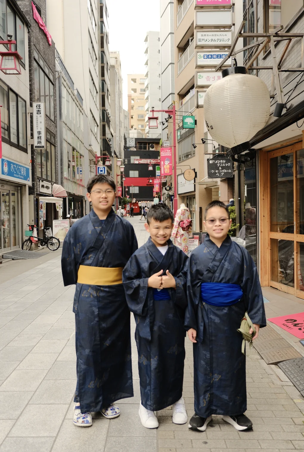 Three boys in navy yukata on an Asakusa street beneath a large paper lantern