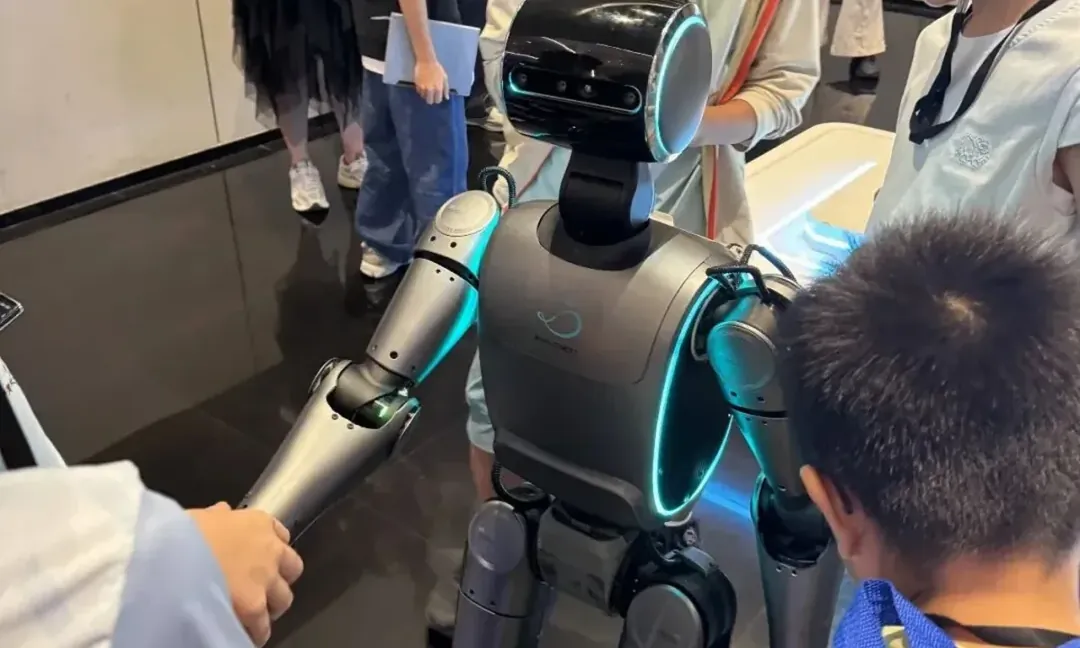A child shaking hands with a humanoid robot at a Shanghai technology showcase
